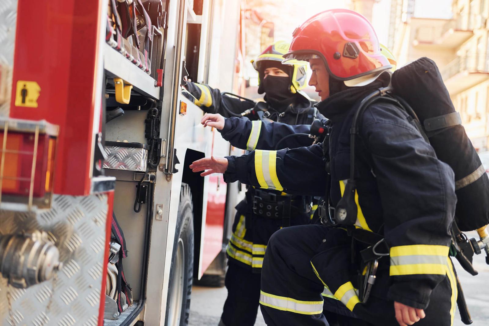 Group of firefighters in protective uniform that outdoors near truck