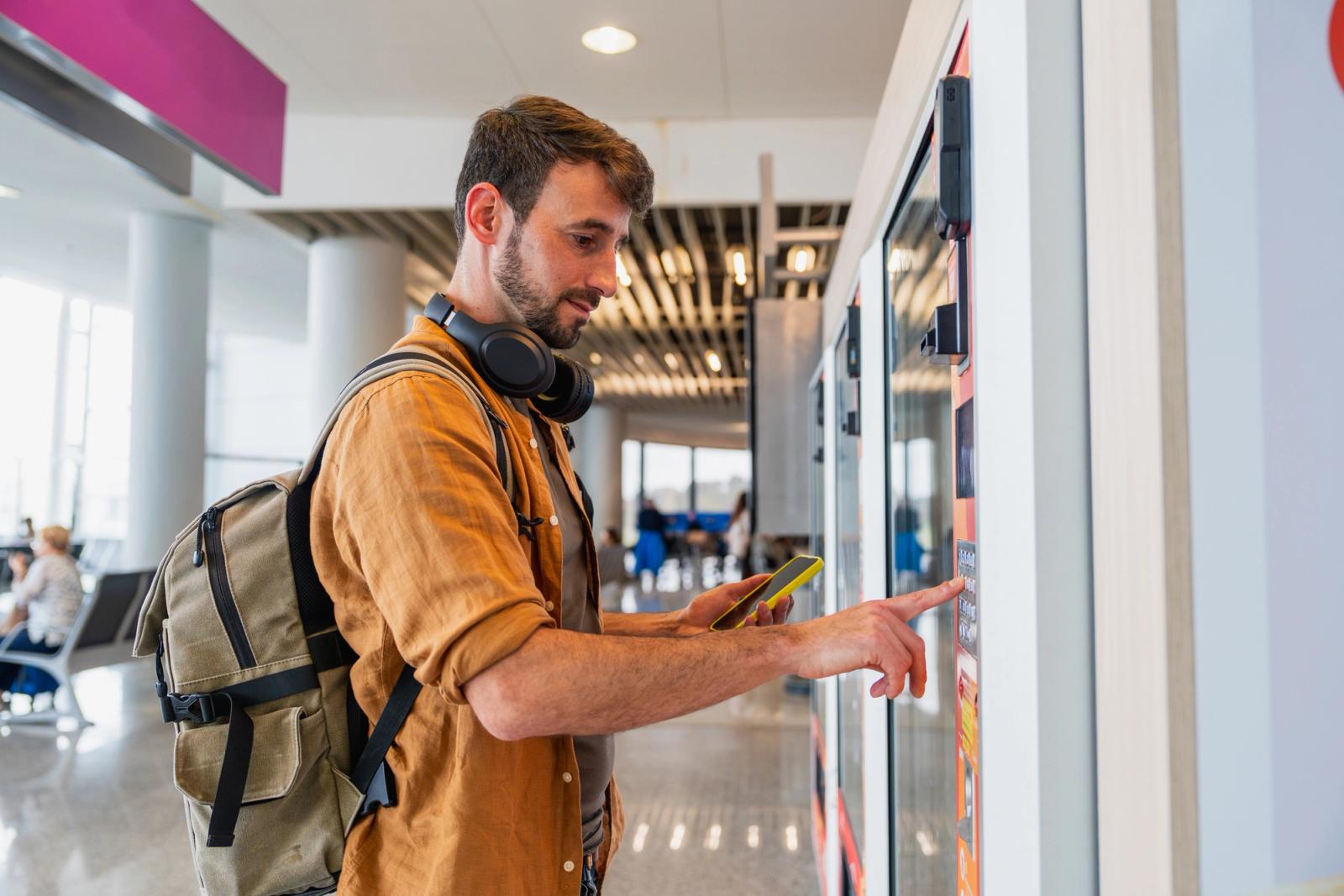 Male traveler buying snack from vending machine at airport