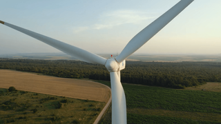 Close up aerial shot of a windmill towering over a rural landscape