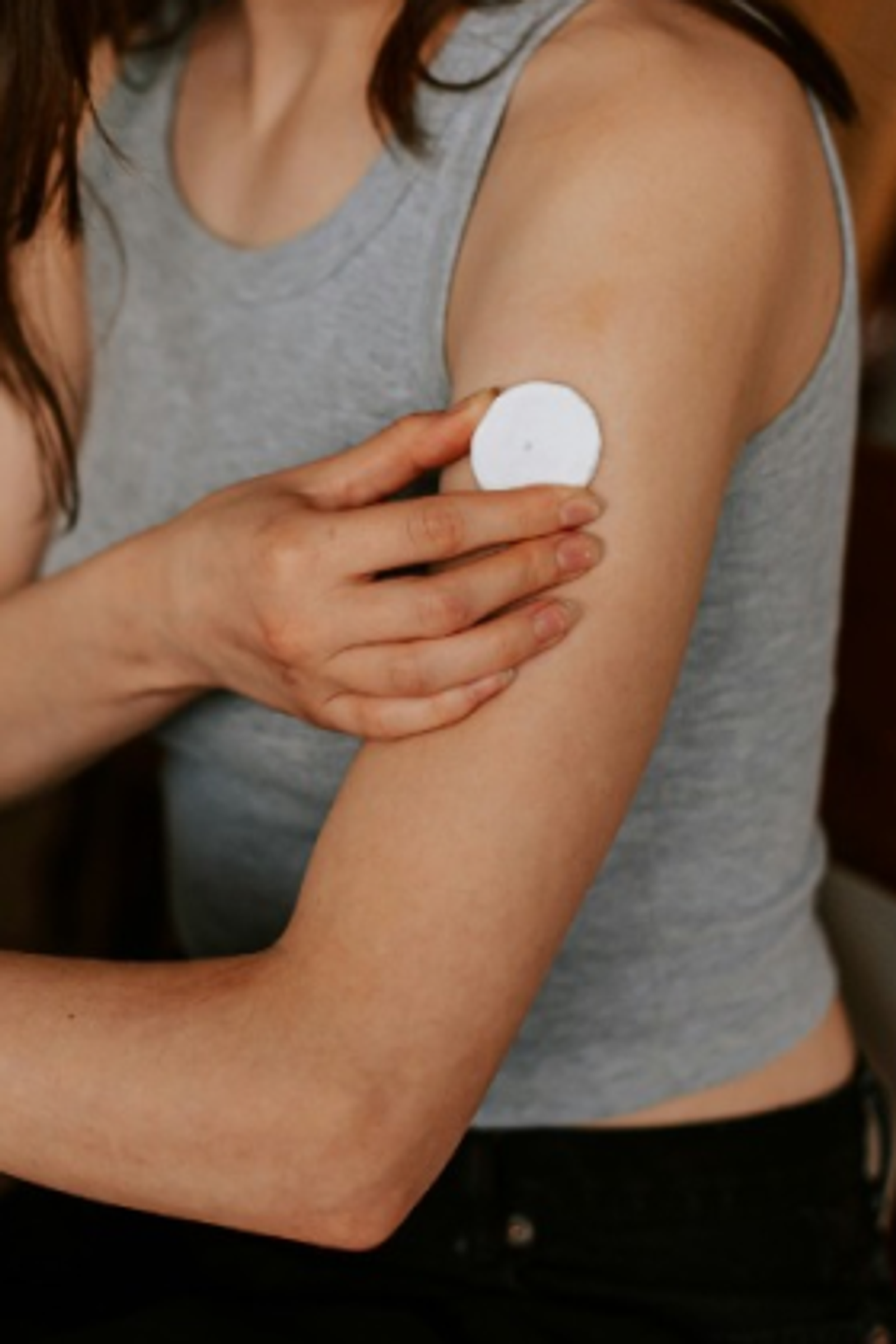 Woman with a wearable glucose monitor on her arm