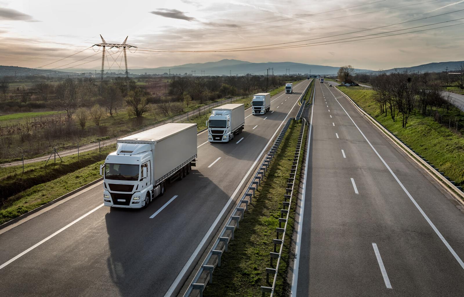 Convoy of 4 trucks on a highway. Highway transportation with trucks.