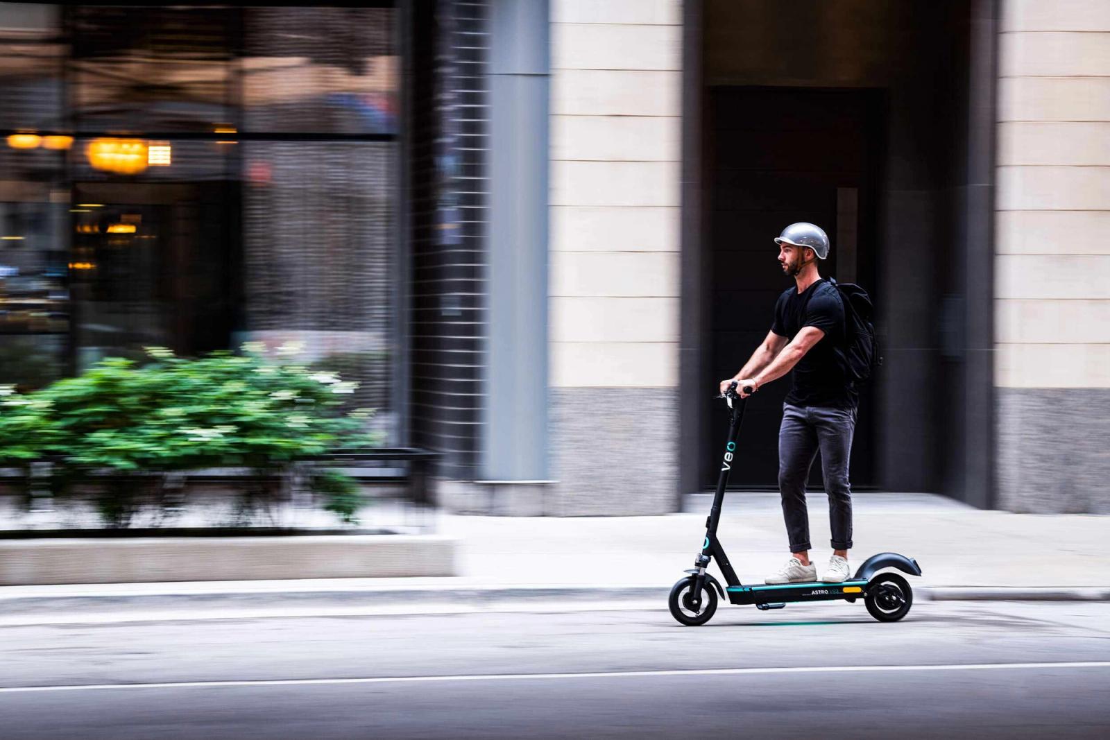 Man riding Veo scooter on a city street