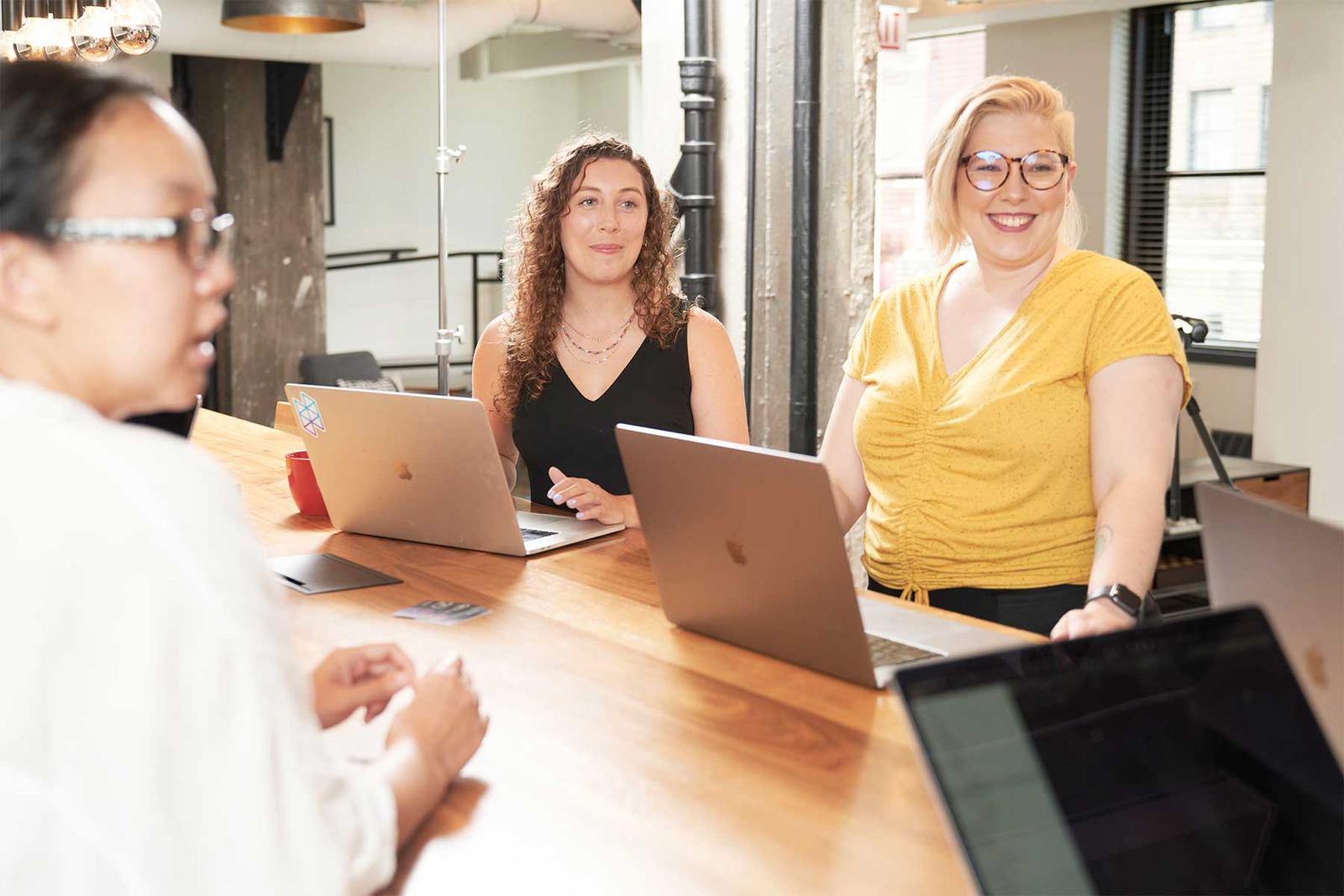 Three Hologram employees sitting together at a conference room table with laptops