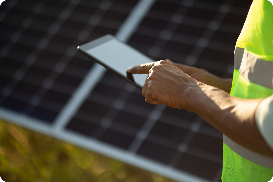 A person uses a tablet near a solar panel