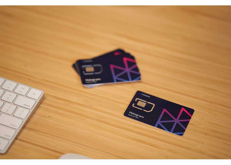 Hologram SIM cards on a wooden table next to a keyboard.