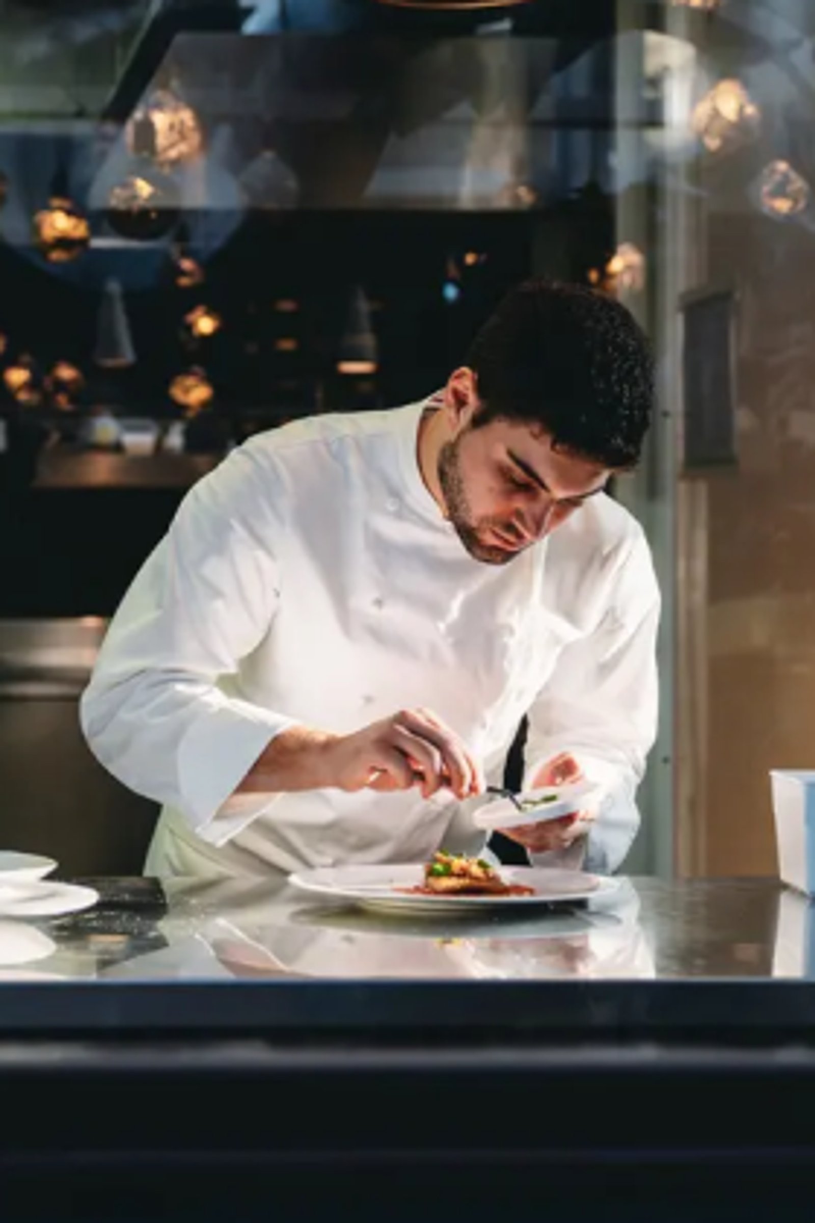 A chef plating a dish in his restaurant's kitchen