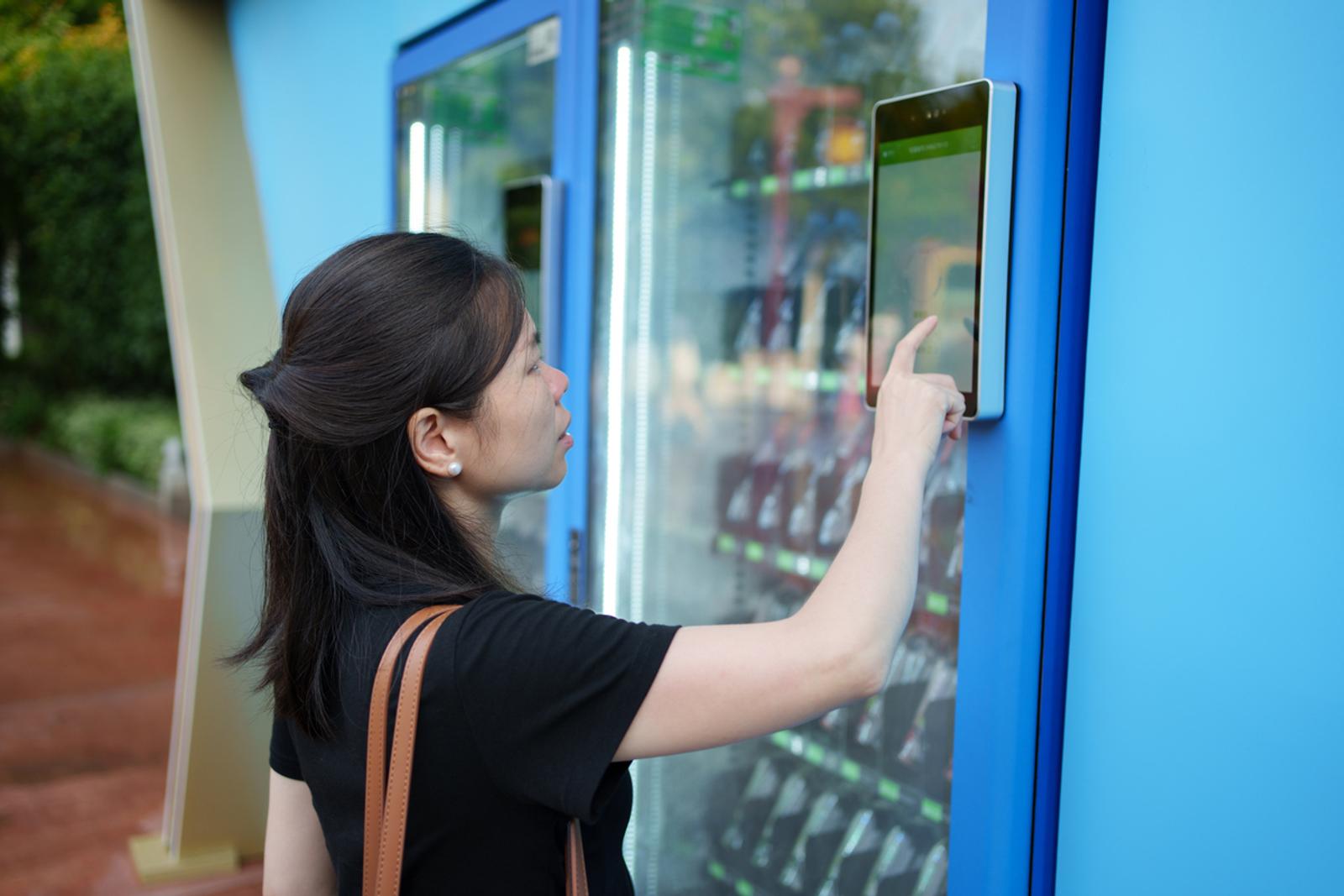 woman at smart vending machine connected by cellular IoT