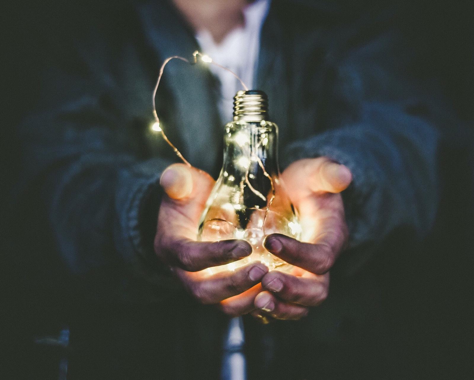 Hands holding glowing lightbulb