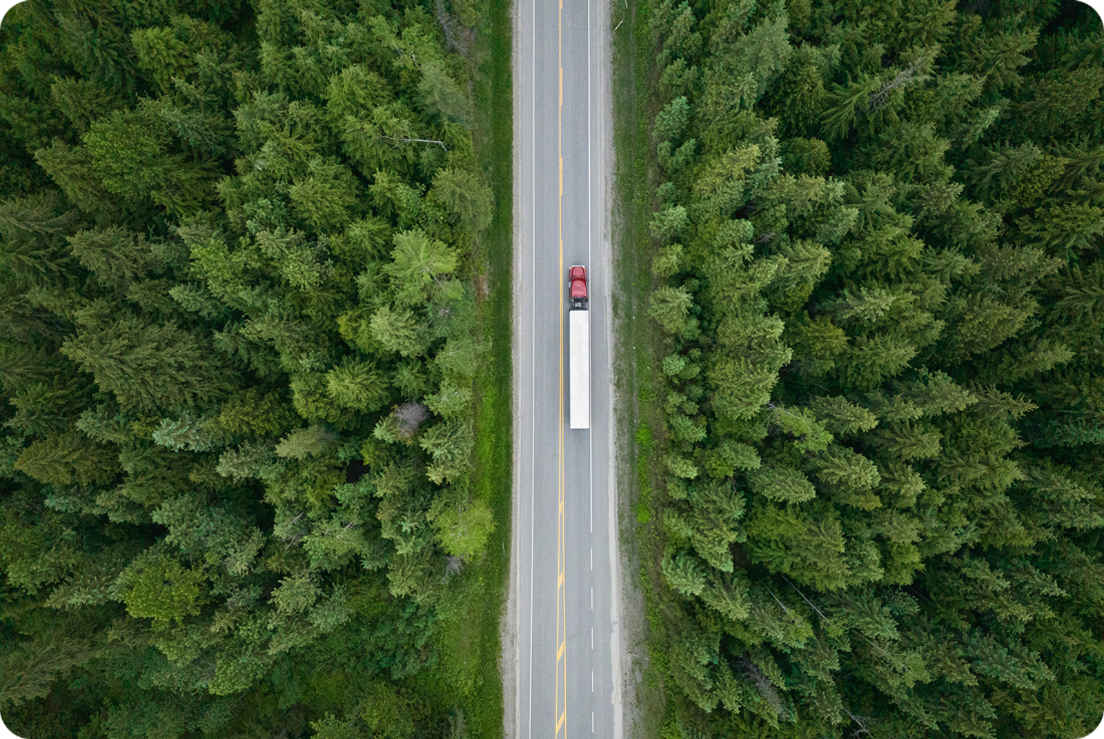 Aerial view of a truck on a highway in a wooded area