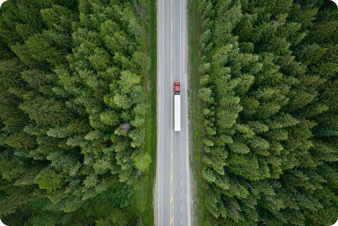 Aerial view of a truck on a highway in a wooded area