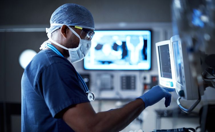 Healthcare provider in scrubs and mask interacting with healthcare technology in hospital setting
