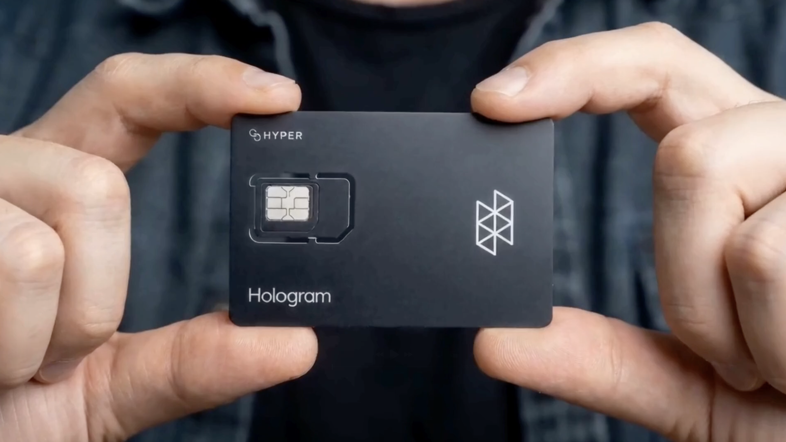 Close up of hands holding a Hologram Hyper SIM card