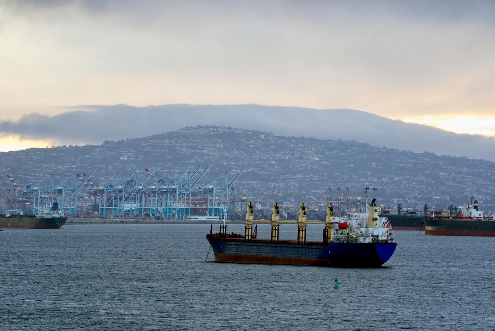 A large barge slowly passes by in a commercial shipping harbor in the Port city of Ensenada, Mexico