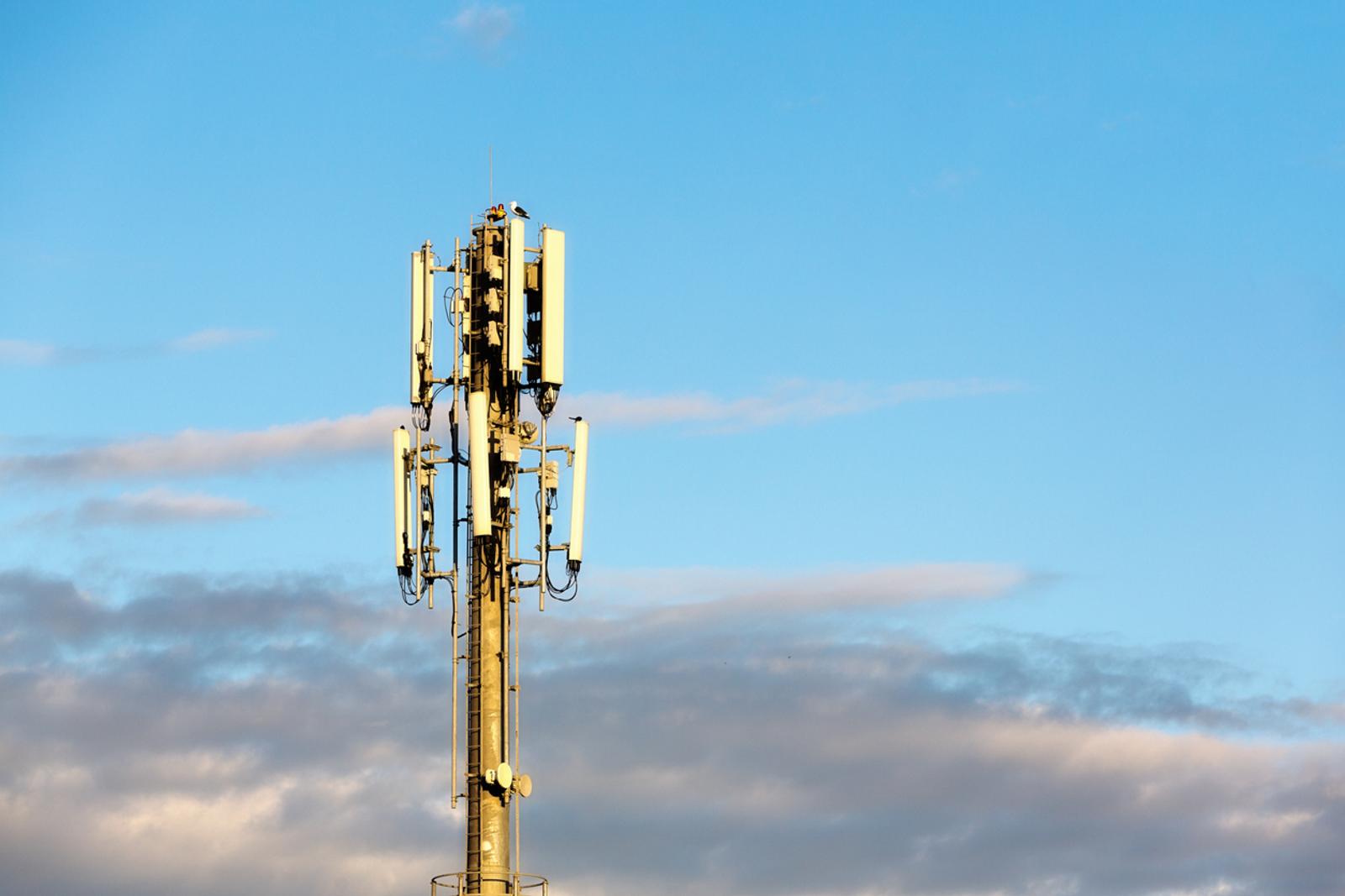 cellular tower in front of blue sky and clouds