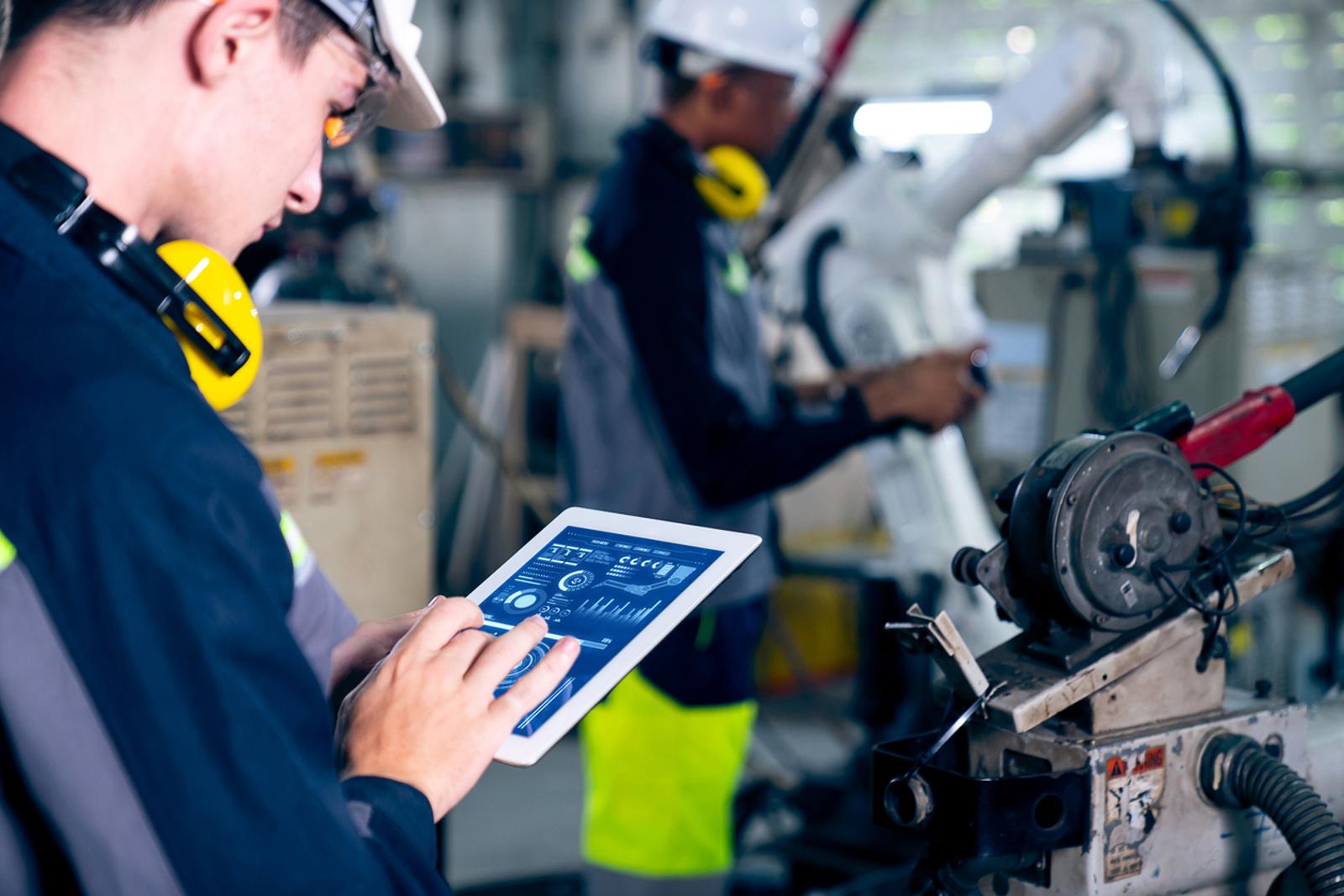 Worker checks machine health on an iPad in a factory