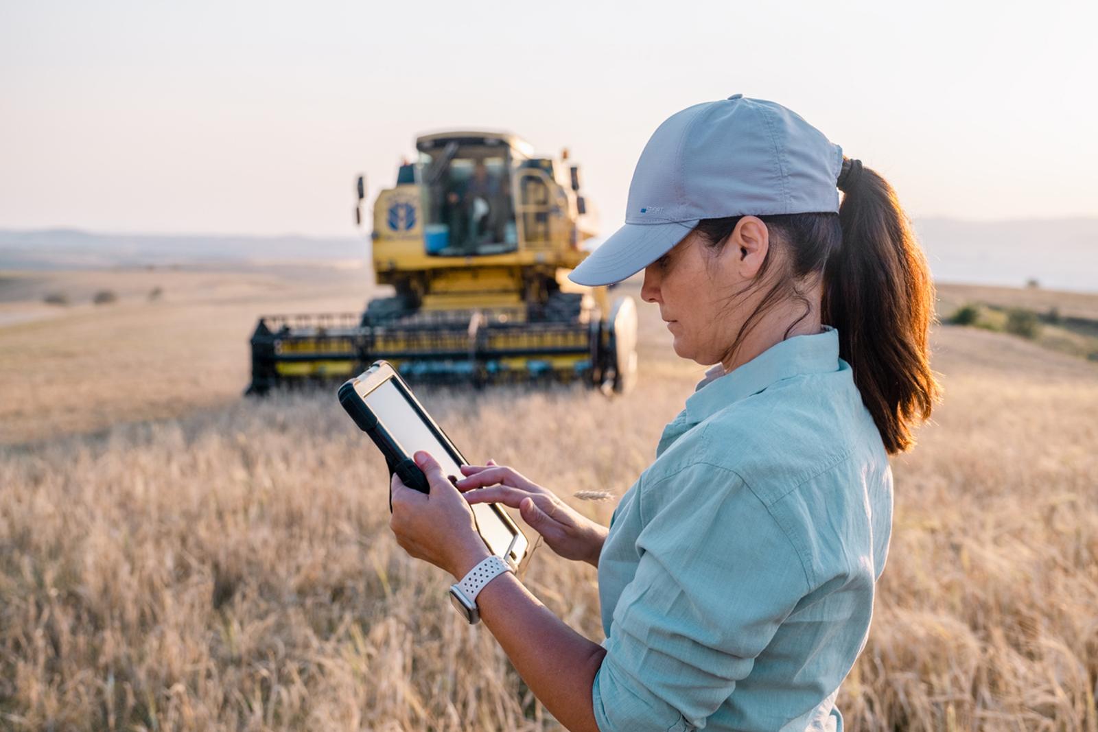 Female farmer holding digital table in farm field