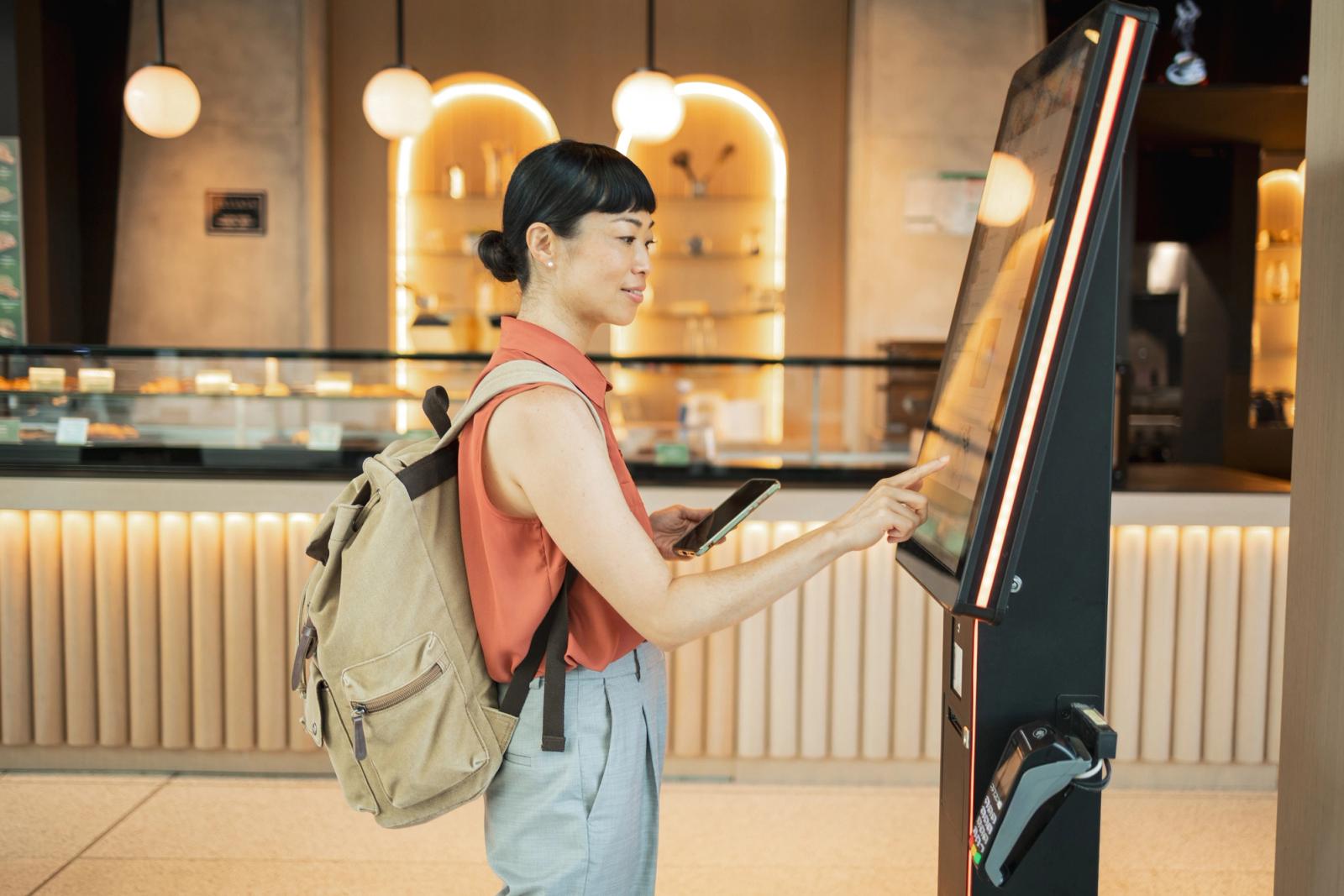 Tourist using self ordering kiosk in cafe