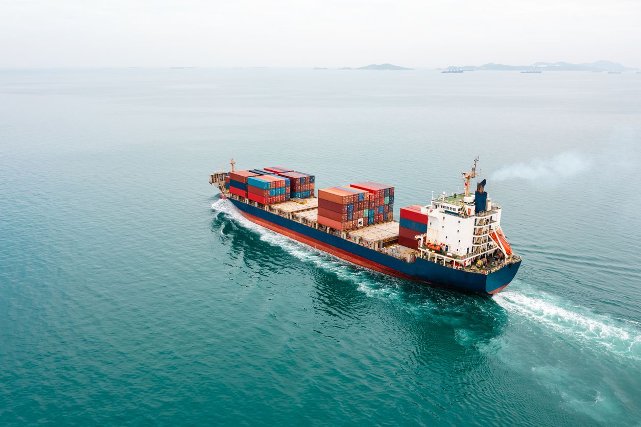 Aerial view of a container ship sailing in sea transporting cargo goods internationally around the world.