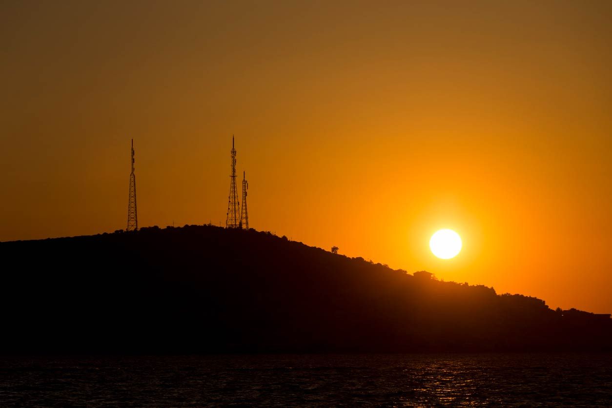 sunset behind hill with cell towers