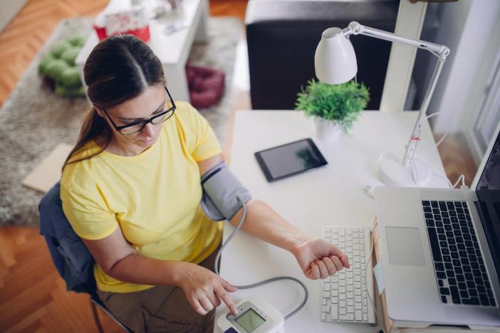 Female at desk with blood pressure monitoring device