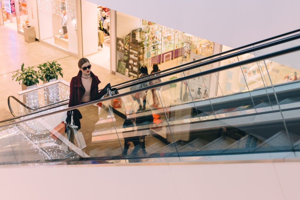 Woman goes up mall escalator