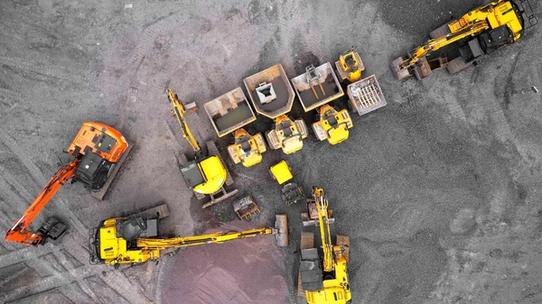 An aerial view of a construction site with yellow and orange diggers