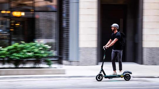 Man riding Veo scooter on a city street