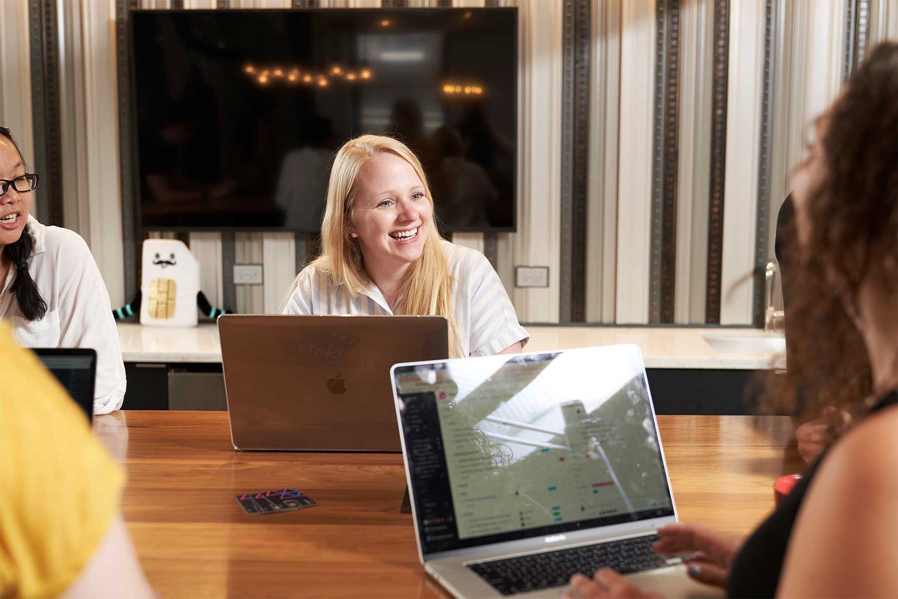 five women sitting at a conference table talking