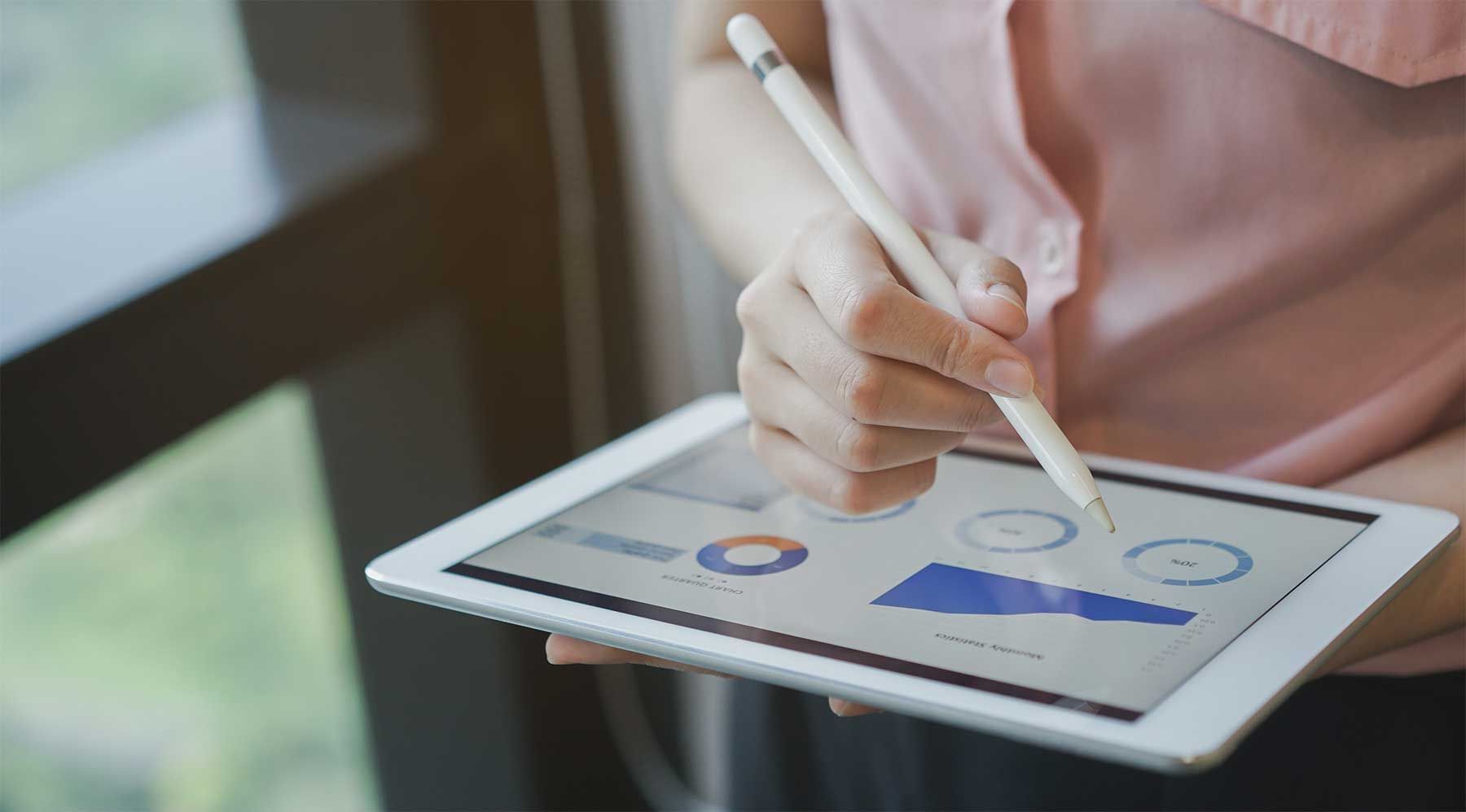 person using a tablet and stylus to monitor analytics