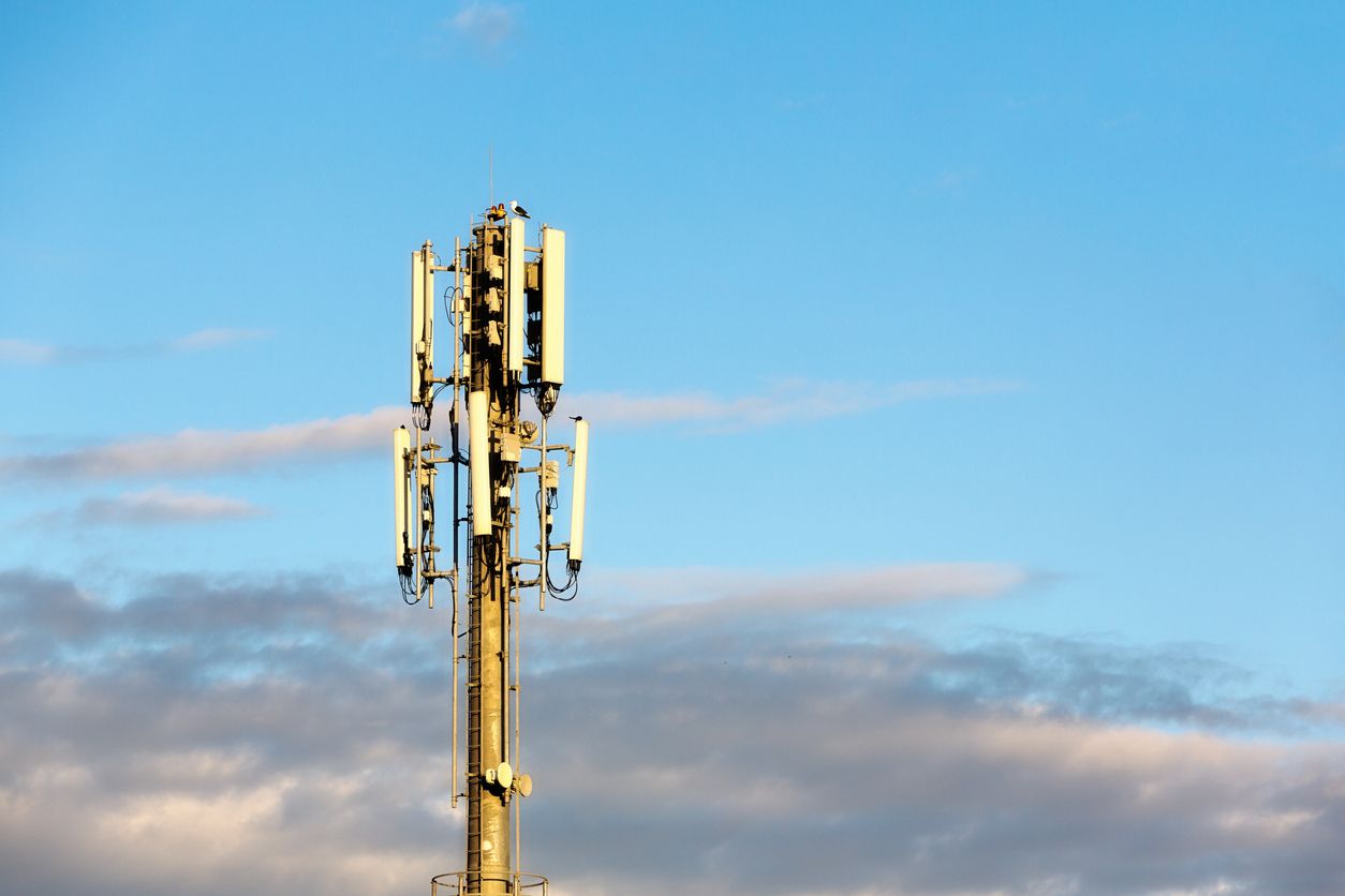 cellular tower in front of blue sky and clouds