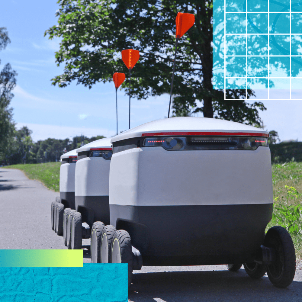 Three autonomous delivery robots rolls down a sidewalk