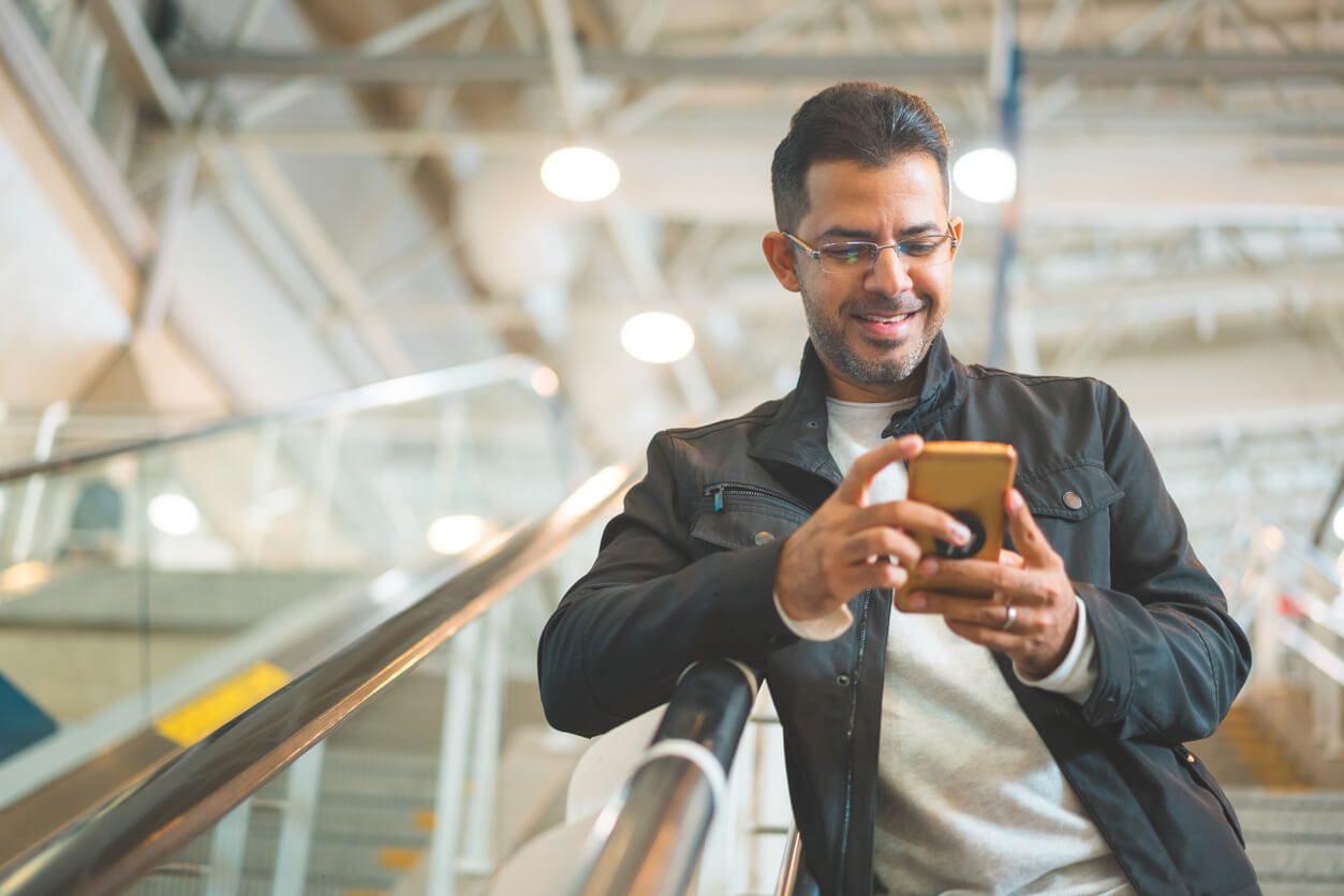 Man with glasses on an escalator looking at his smartphone