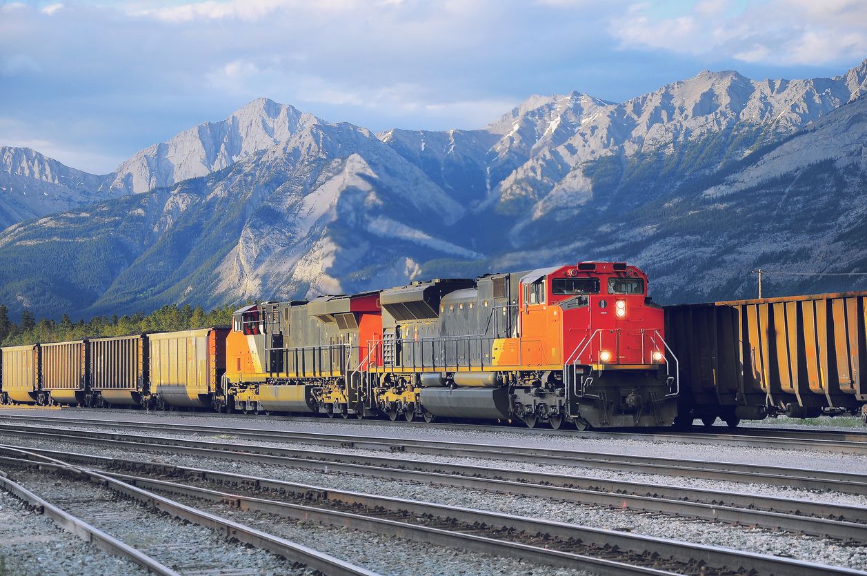 Freight container train in the forefront with a mountain range in the background.