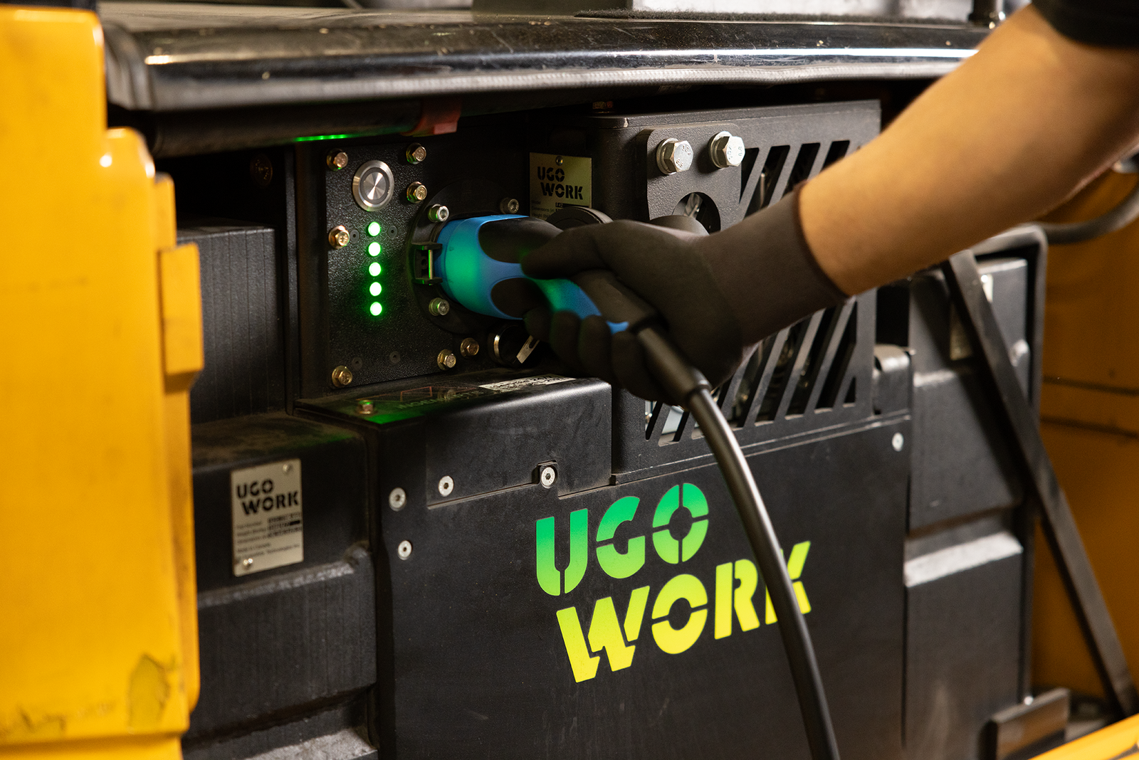 A hand plugging a charger into a UgoWork battery