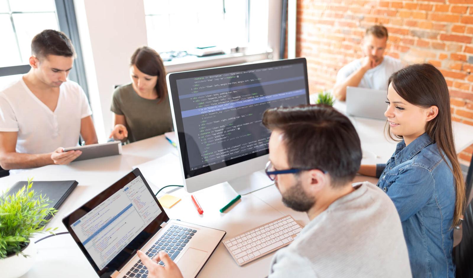 People around a conference room desk looking at computers