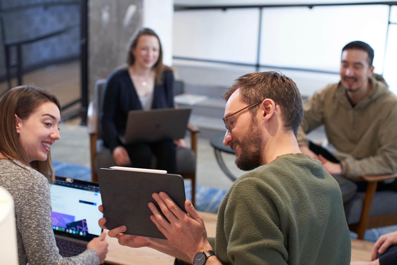 People huddled around a table at the Hologram office looking at an iPad