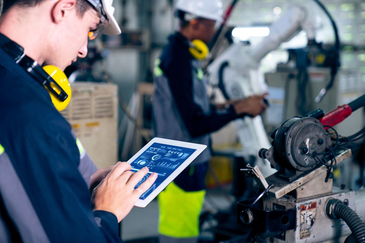 Worker checks machine health on an iPad in a factory