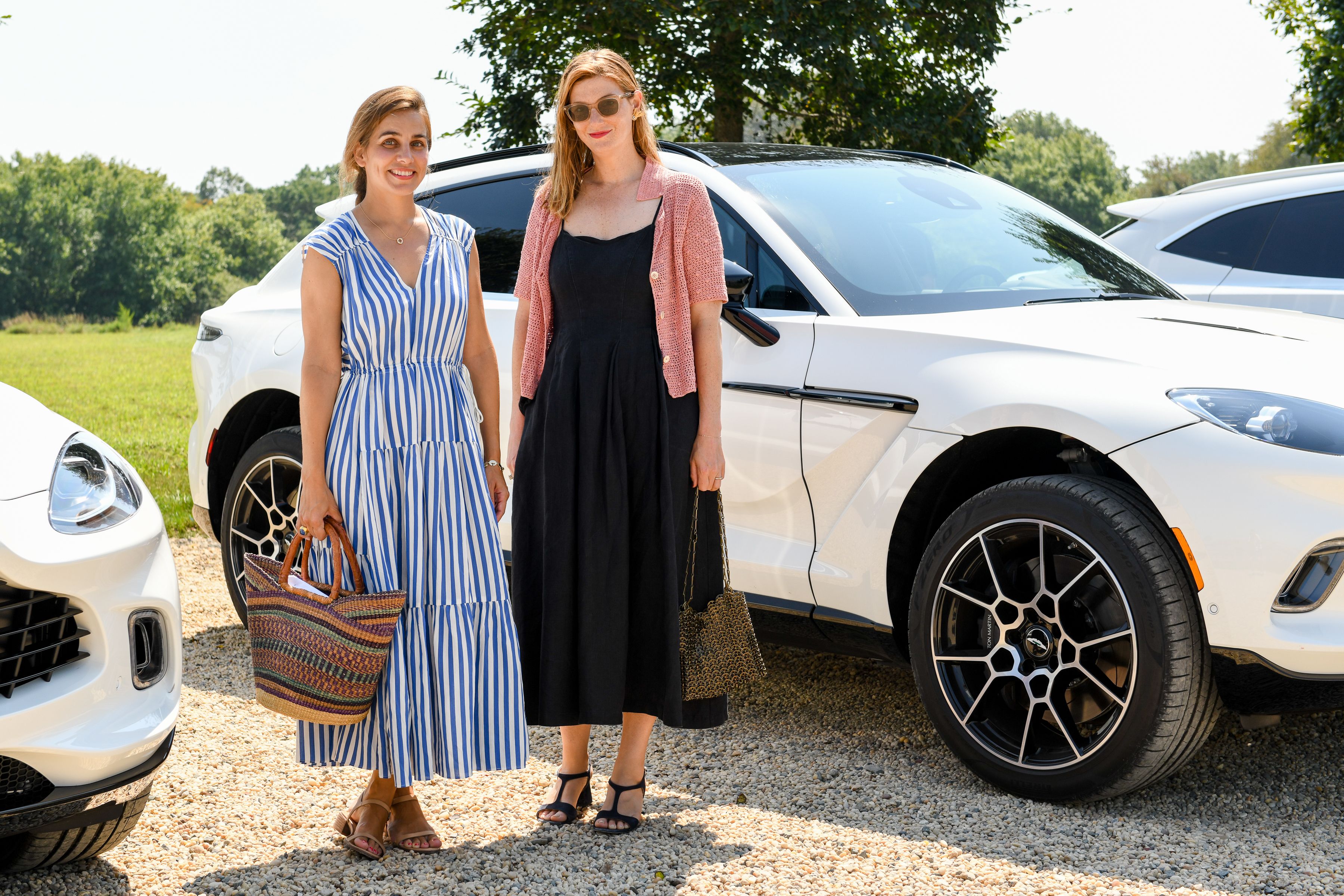 Two women standing in front of a car