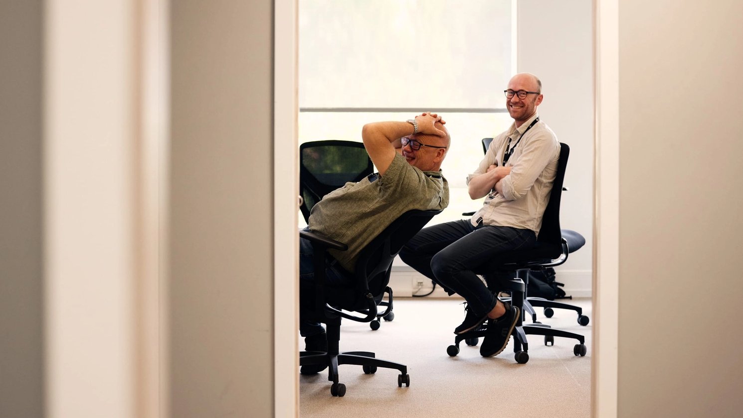 To menn sitter avslappet på hver sin kontorstol