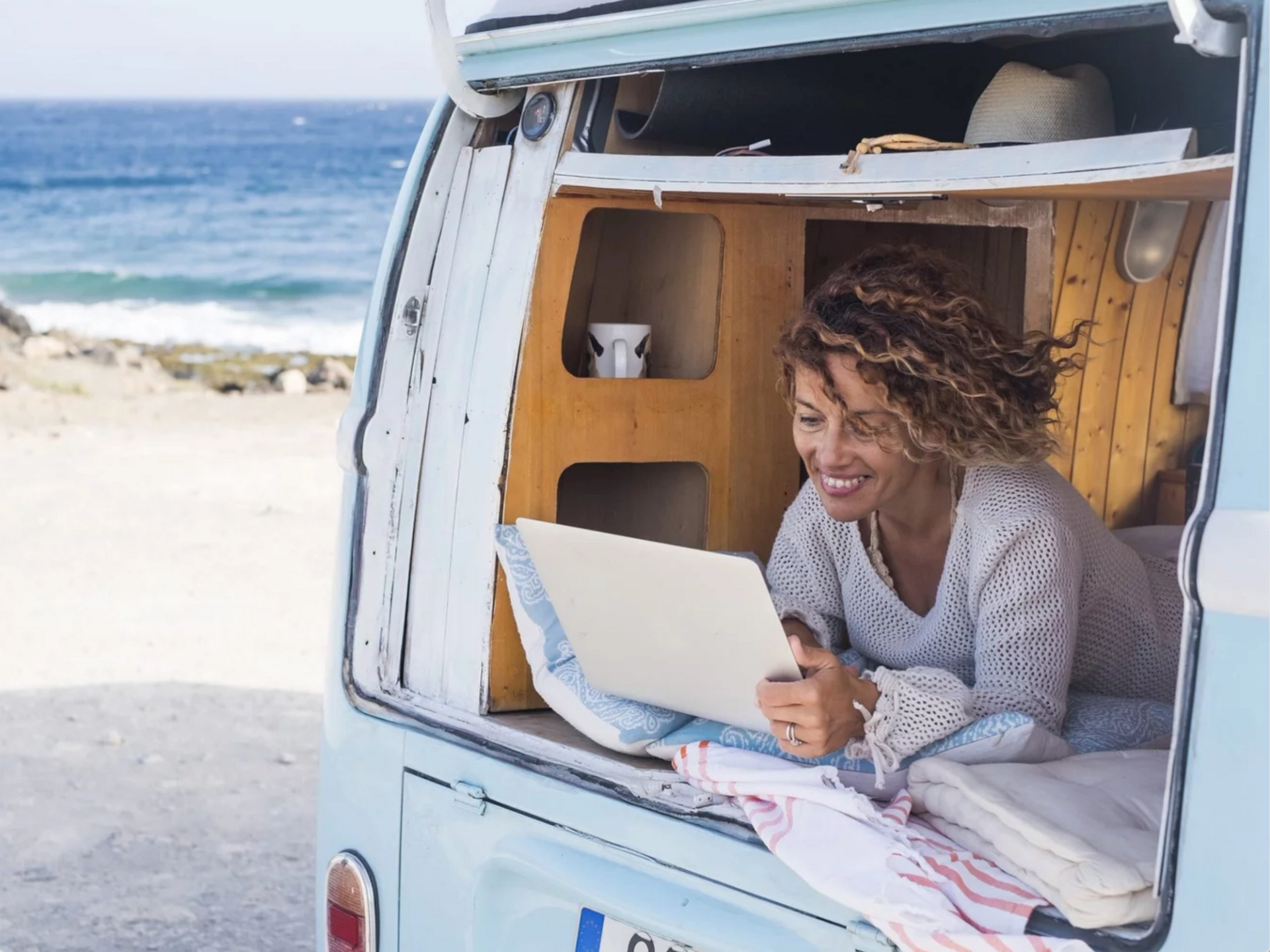 Woman working remotely from the back of a van on the beach