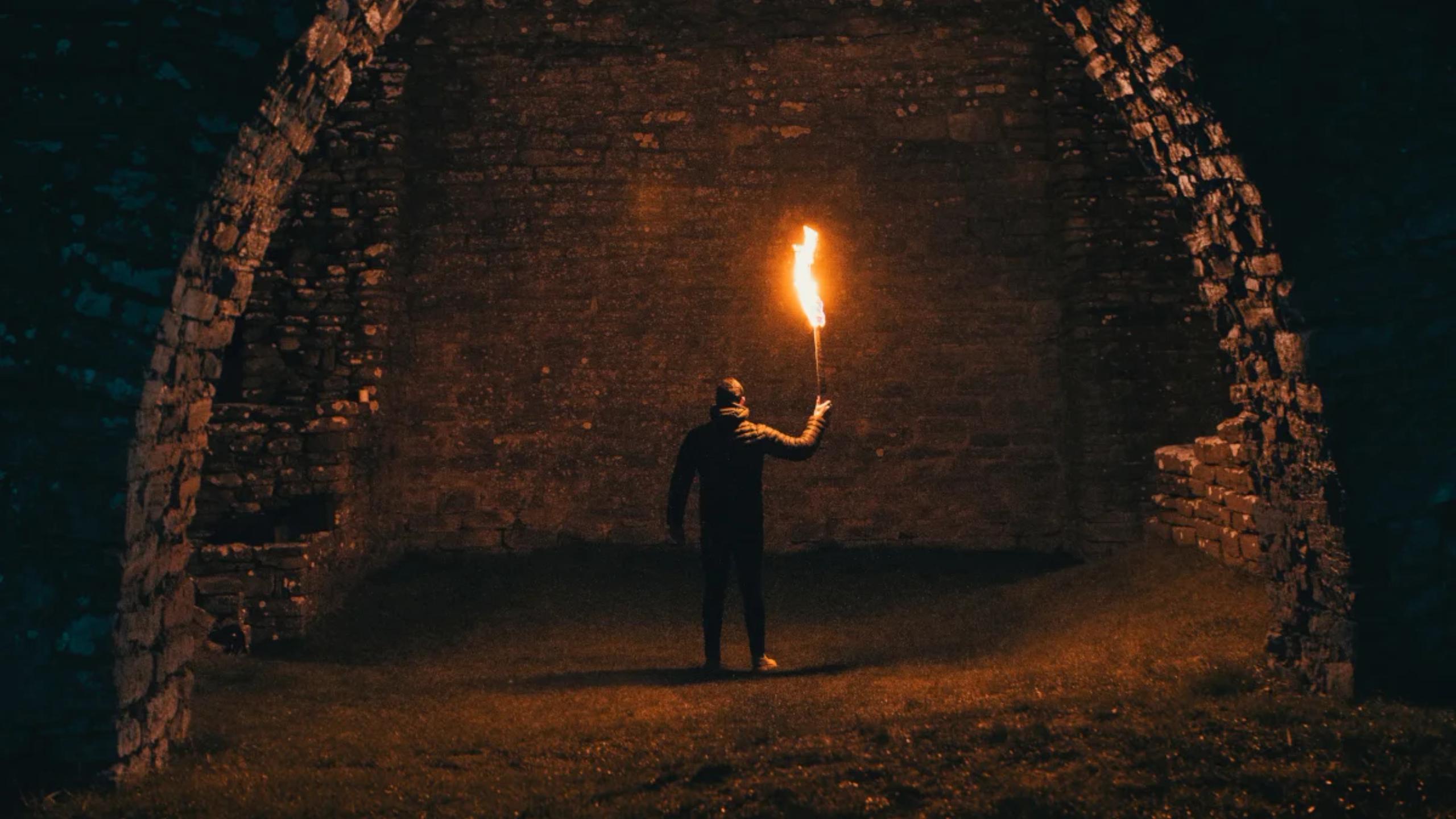 Man holding torch standing in dark cave