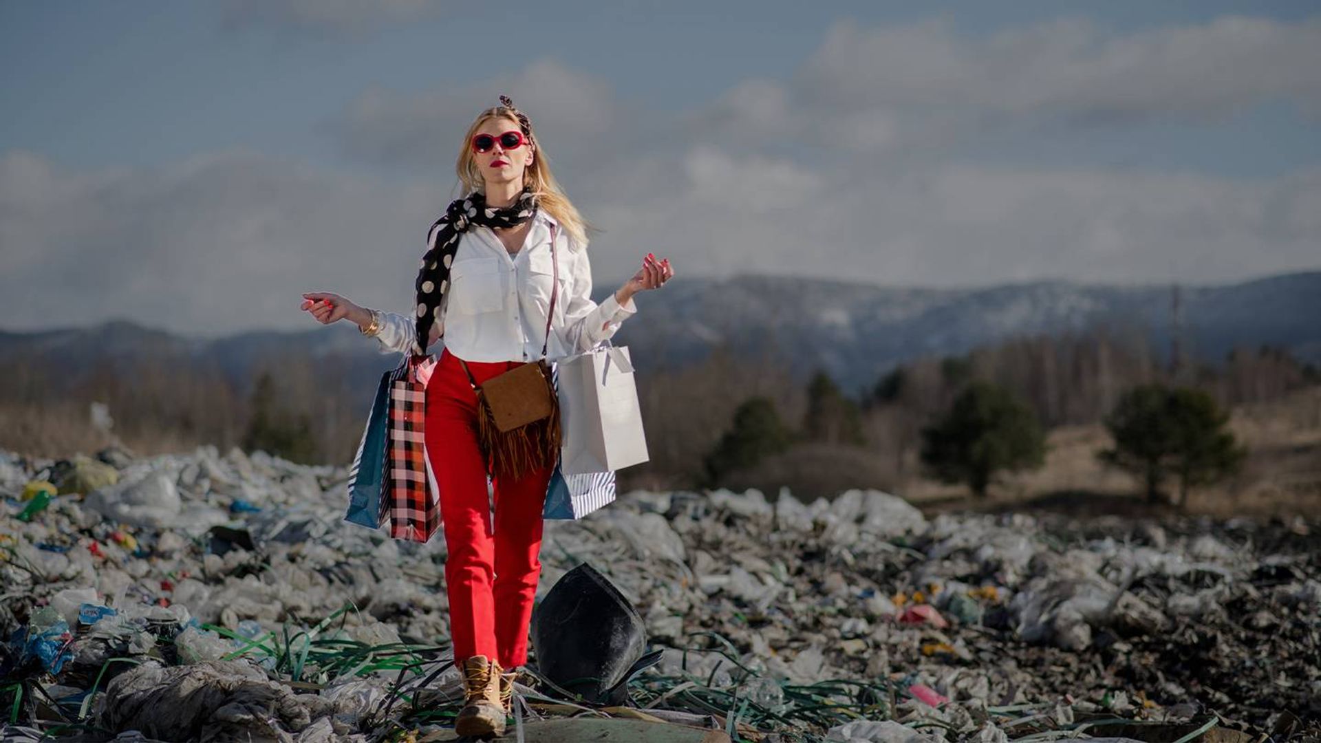 Model walking through piles of discarded clothes