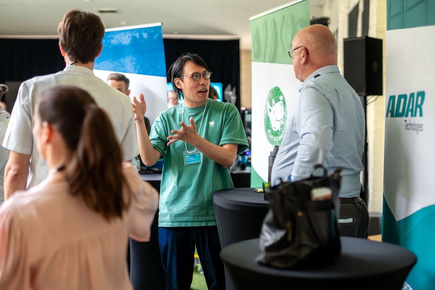 Someone talking to visitors at a startup showcase, in front of their company banner