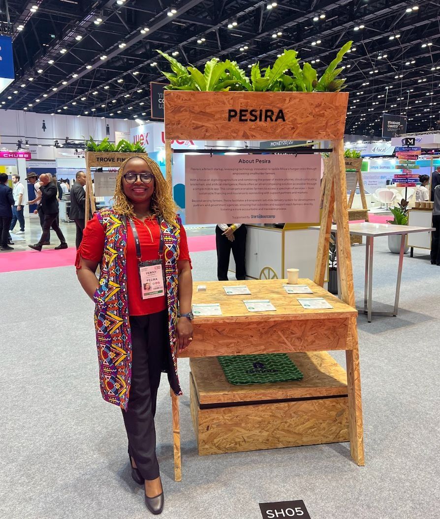Someone at the Pesira stand at a trade show, beside a board about the company