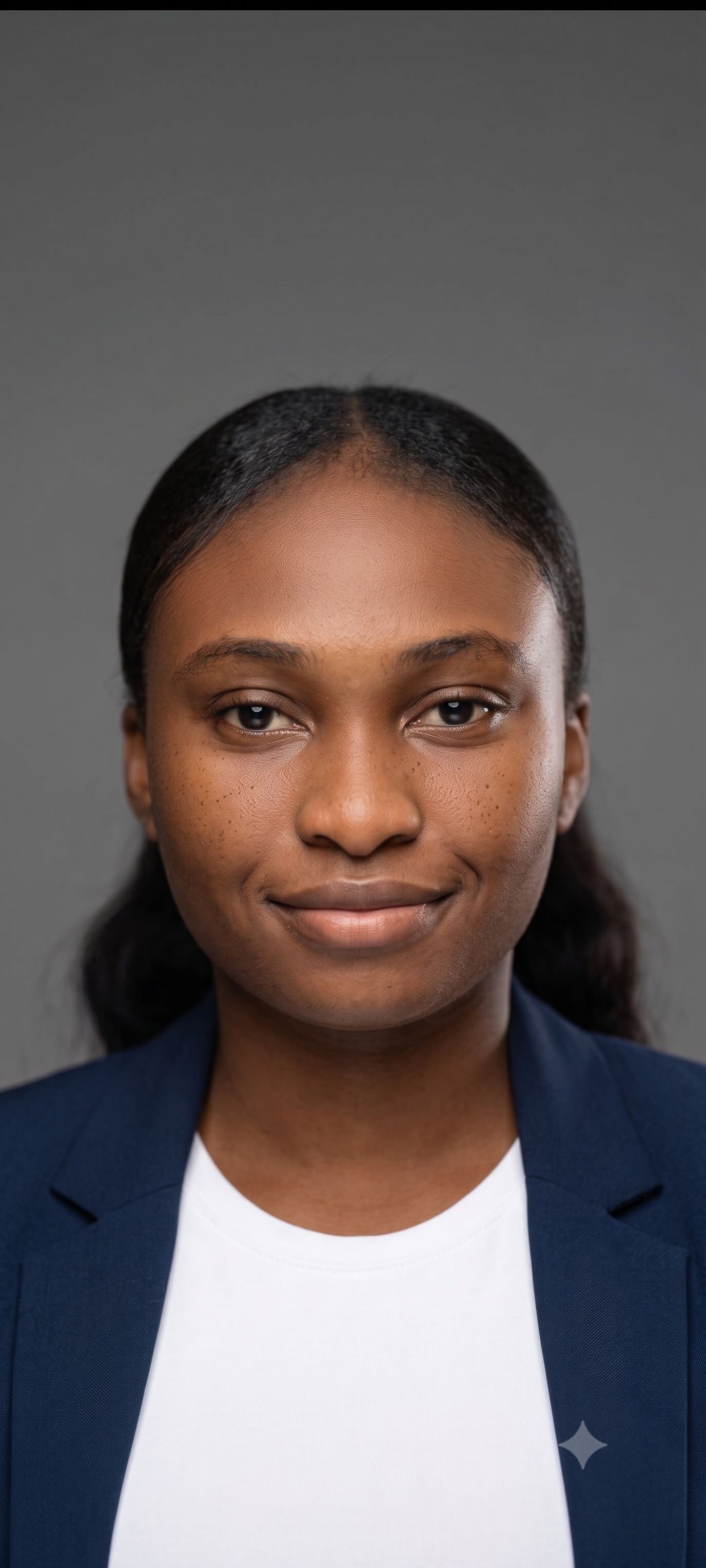 Maureen Samuel — studio portrait, in a navy blazer over a white top against a grey backdrop.
