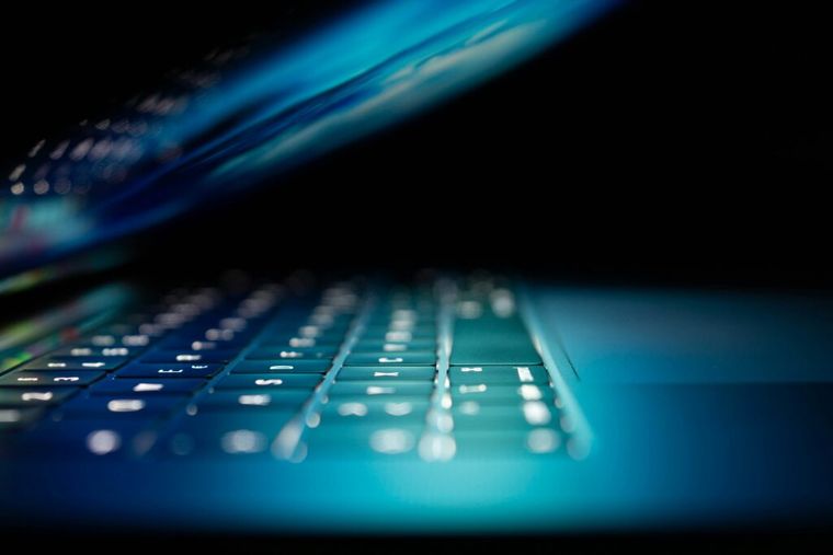 Open laptop glowing on a desk in a dark room.