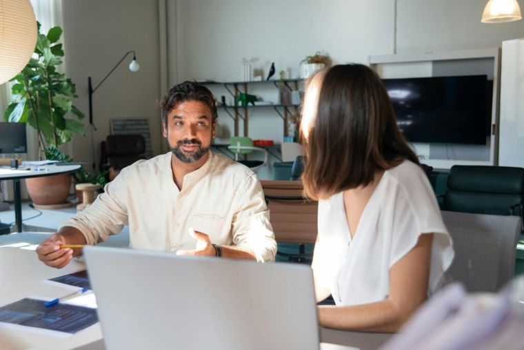 A man with facial hair engages in conversation with a woman in an office setting, discussing duty drawback documentation.