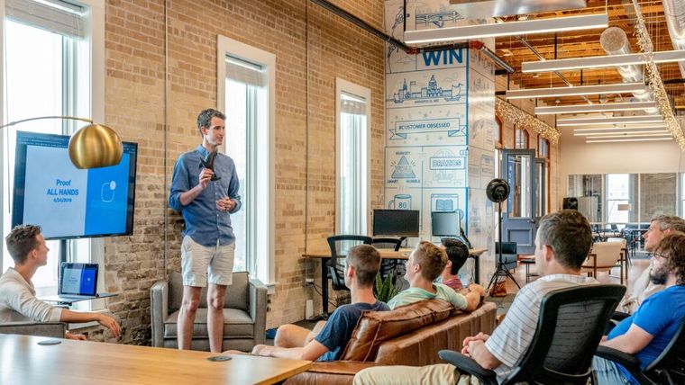 A speaker presents to a group of professionals in a bright, modern workspace—illustrating a founder sharing strategies like deferred compensation plans to reduce current tax burdens and invest in long-term financial growth.