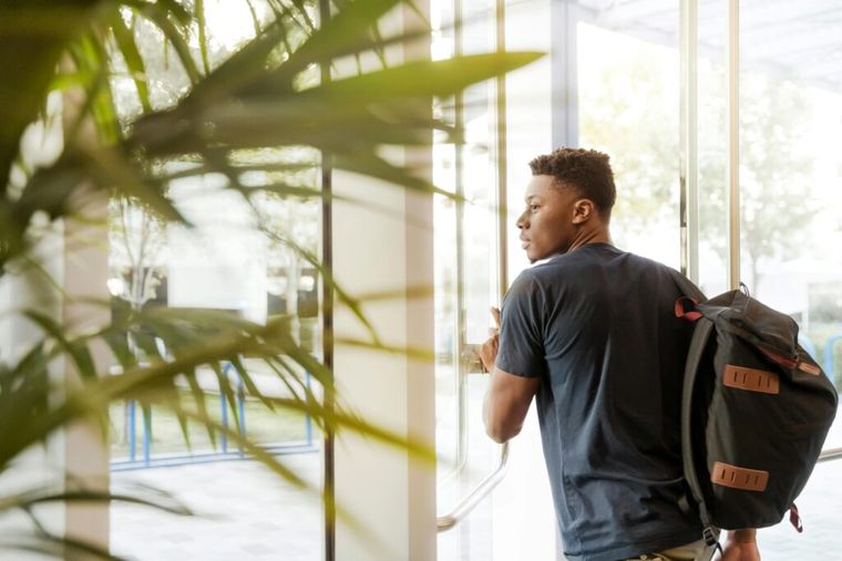 A man with a backpack looks out a window, evoking a sense of reflection and planning—symbolic of individuals reevaluating their retirement and inheritance strategies in response to changes brought by the SECURE Act 2.0.