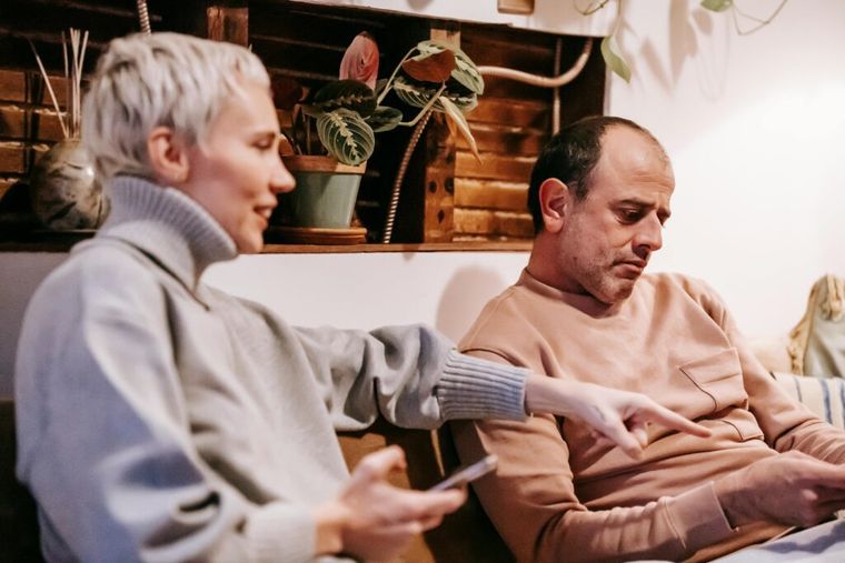A middle-aged couple sits on their living room sofa using a tablet and smartphone—representing retirees or beneficiaries exploring digital tools and strategies to manage inherited IRAs and reduce taxes under SECURE Act 2.0.